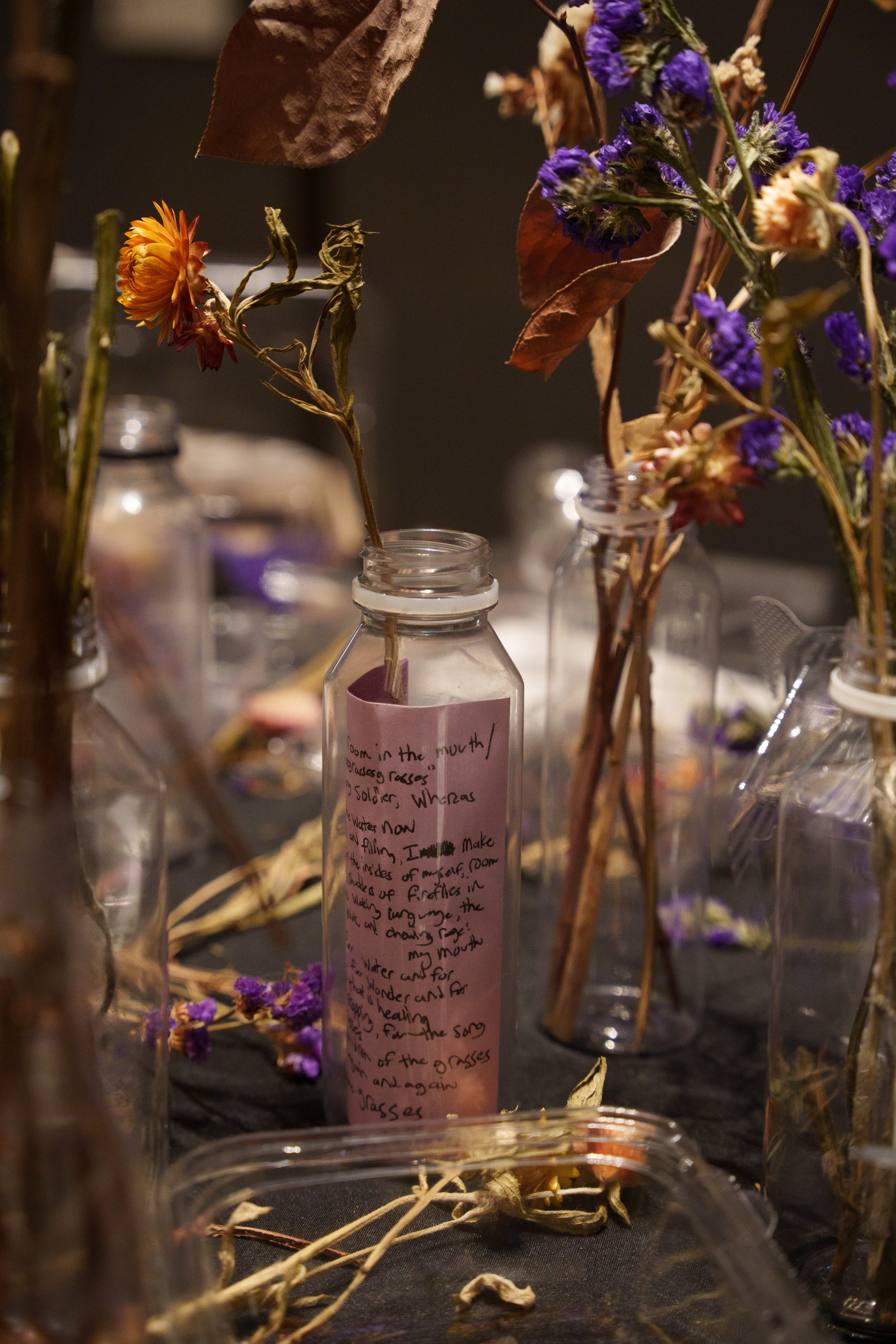Detail image of dried flowers, glass vases, black text printed on paper