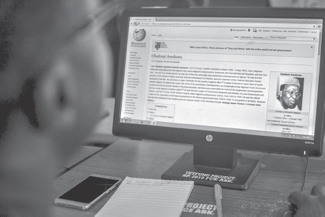 A person looking at a computer screen where it displays a Wikipedia page on Obafemi Awolowo.