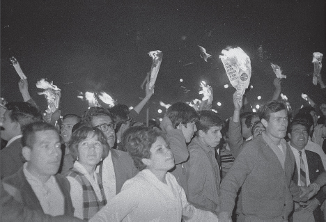 A 1968 picture of people in a protest in Mexico City, some holding hands, some holding burning pieces of paper.