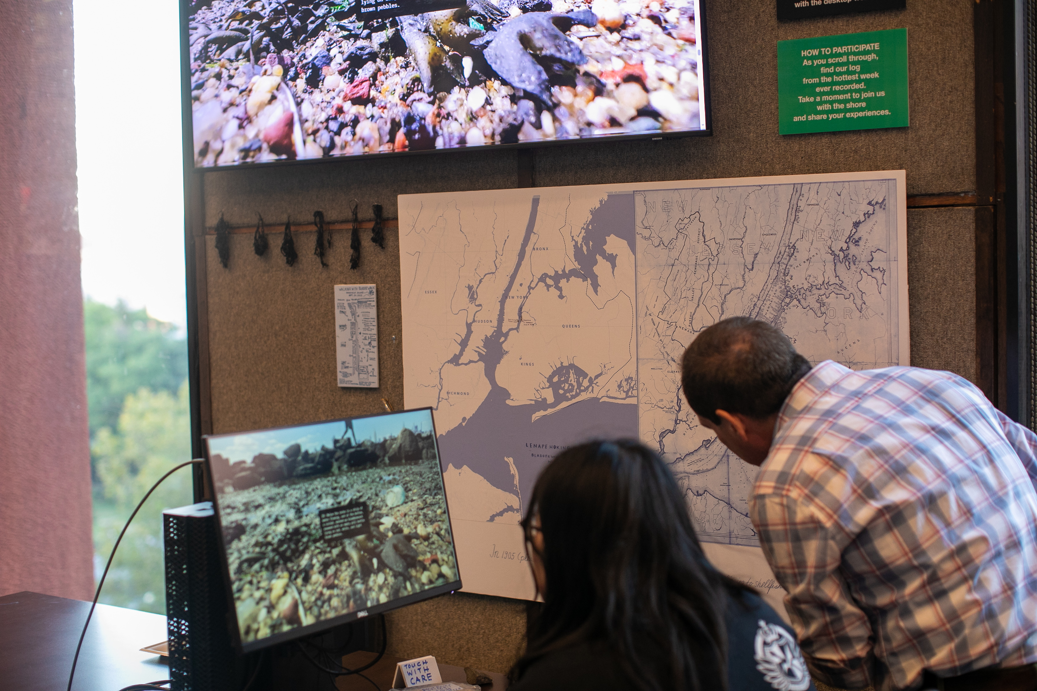 Photograph of people at a computer terminal and looking at a map on a wall