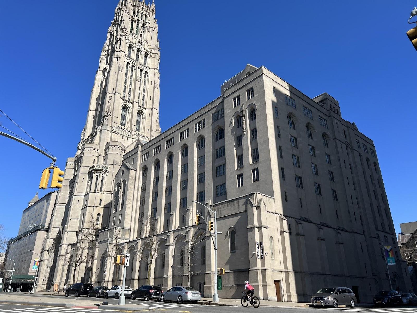 A tall building with a tall tower with Detroit Masonic Temple in the background

Description automatically generated