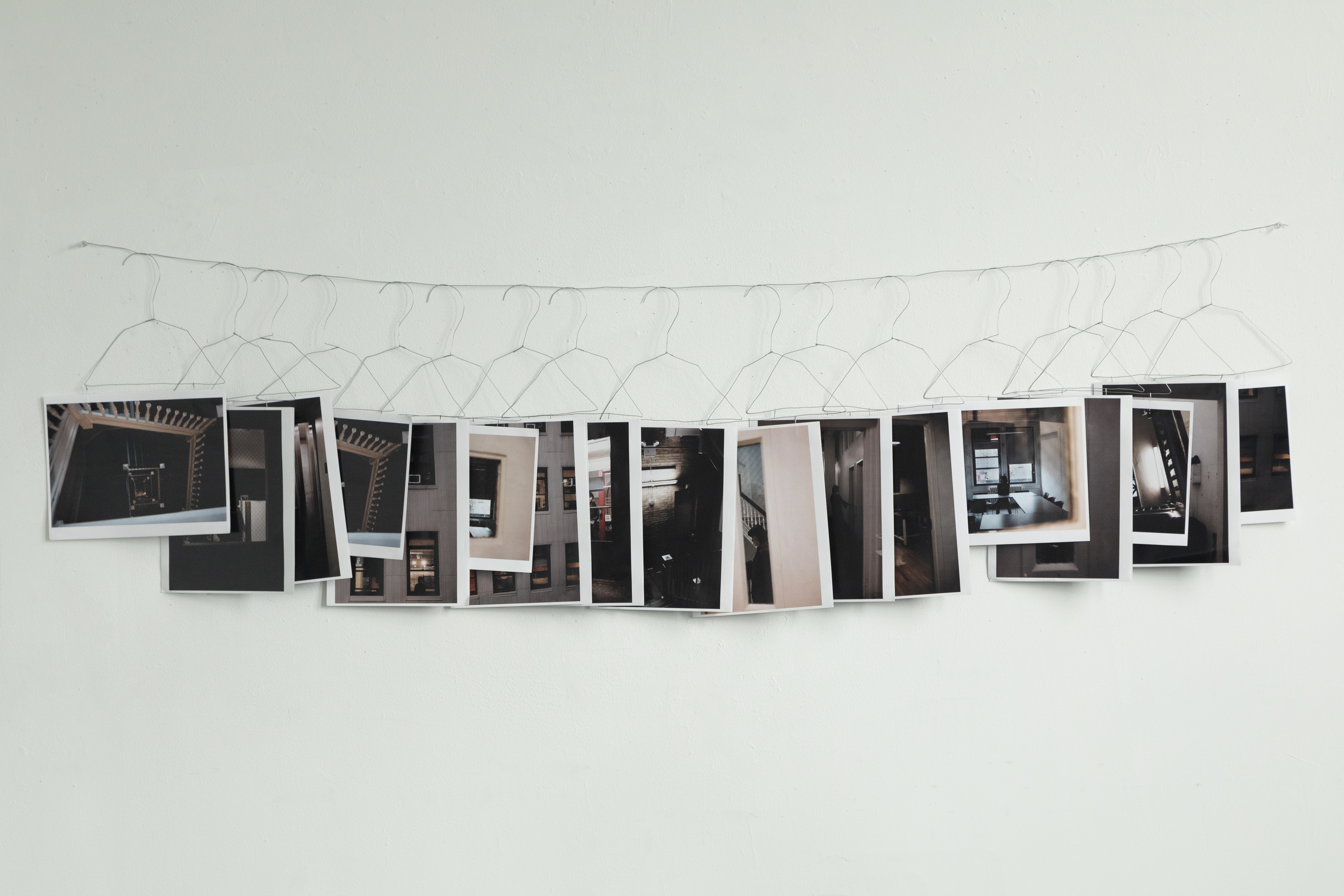 Image of 17 printed color photos featuring stairwells and other building artifacts, attached to wire clothes hangers